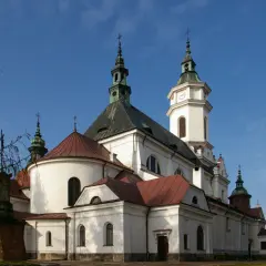 Kościół z wieżą zegarową i krzyżami na tle błękitnego nieba.
