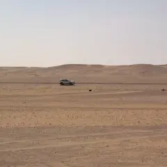 Samochód przemierza pustynny krajobraz Arabii Saudyjskiej. Czy Arabia Saudyjska jest bezpieczna? Podróż przez bezkresne piaski.