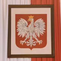 Obraz przedstawia godło polskie – białego orła w koronie na czerwonej tarczy.
