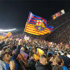 Tłum kibiców na stadionie unosi flagę FC Barcelona, symbol Katalonii.
