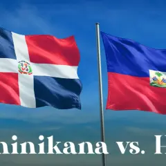 Dwie flagi powiewają na wietrze: dominikana flaga z białym krzyżem i herbem oraz flaga Haiti.