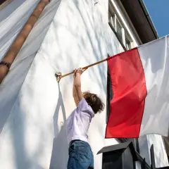 Dziecko zdejmuje biało-czerwoną flagę. Zgodnie z tradycją, flagę zdejmuje się po 3 maja, gdy minie czas jej wywieszenia.
