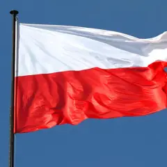 Biało-czerwona flaga Polski powiewa na maszcie na tle błękitnego nieba. Czy flaga może wisieć cały rok? Tak, symbol dumy narodowej jest zawsze na miejscu.