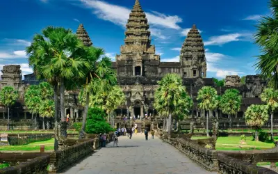 Majestatyczna świątynia Angkor Wat, symbol Kambodży, otoczona palmami pod błękitnym niebem.