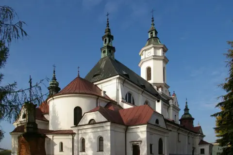 Kościół z wieżą zegarową i krzyżami na tle błękitnego nieba.