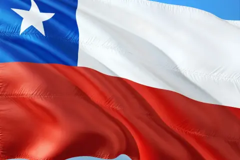 Flaga Chile powiewa na wietrze. Biały pas, czerwony pas i niebieski kwadrat z białą gwiazdą symbolizują ten kraj.