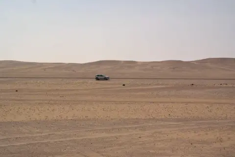 Samochód przemierza pustynny krajobraz Arabii Saudyjskiej. Czy Arabia Saudyjska jest bezpieczna? Podróż przez bezkresne piaski.