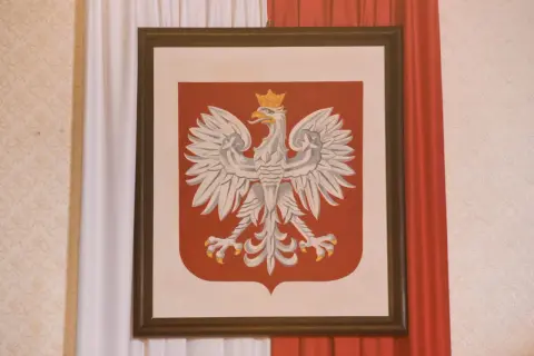 Obraz przedstawia godło polskie – białego orła w koronie na czerwonej tarczy.
