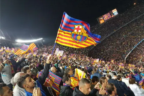 Tłum kibiców na stadionie unosi flagę FC Barcelona, symbol Katalonii.