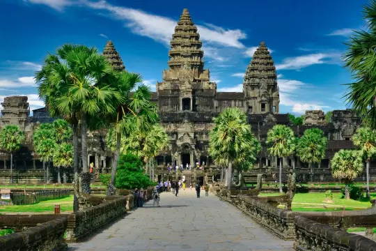 Majestatyczna świątynia Angkor Wat, symbol Kambodży, otoczona palmami pod błękitnym niebem.