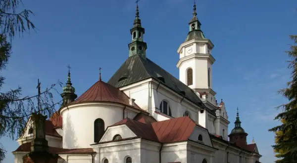 Kościół z wieżą zegarową i krzyżami na tle błękitnego nieba.