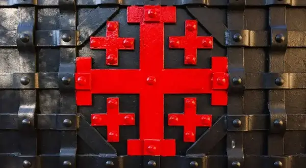 Czerwony krzyż jerozolimski, symbol rycerzy, zdobi masywną, czarną, metalową bramę.