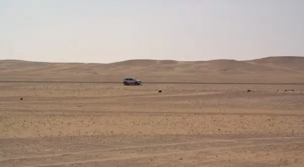 Samochód przemierza pustynny krajobraz Arabii Saudyjskiej. Czy Arabia Saudyjska jest bezpieczna? Podróż przez bezkresne piaski.
