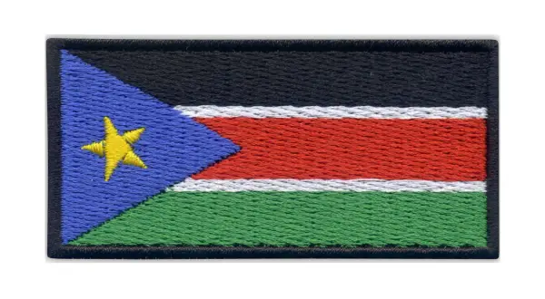 Naszywka z flagą Sudanu Południowego. Czarny pas na górze, pod nim biały, czerwony i zielony pas. Z lewej strony niebieski trójkąt z żółtą gwiazdą.