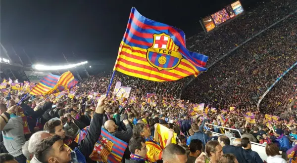 Tłum kibiców na stadionie unosi flagę FC Barcelona, symbol Katalonii.
