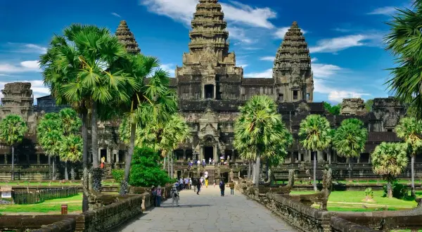 Majestatyczna świątynia Angkor Wat, symbol Kambodży, otoczona palmami pod błękitnym niebem.