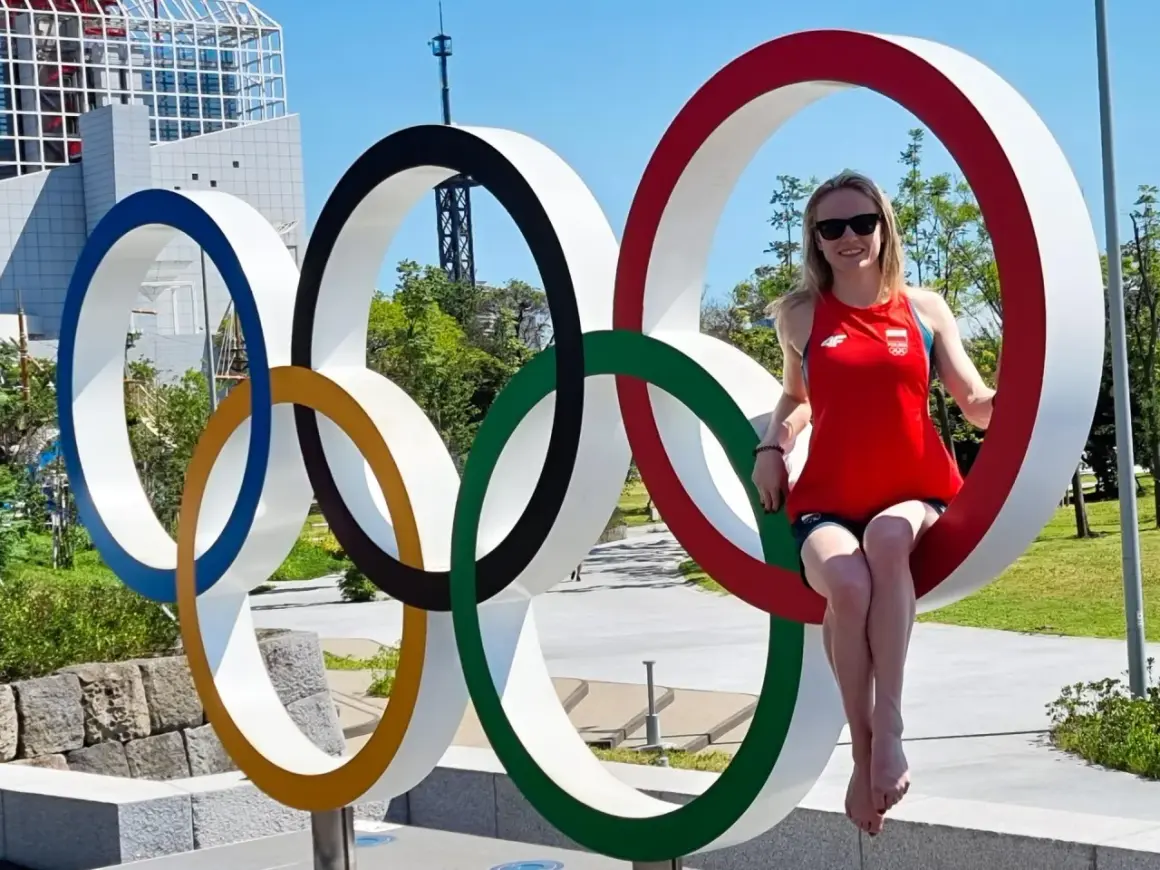 Kobieta w czerwonej koszulce z polską flagą siedzi na jednym z kół symbolizujących flagę olimpijską.
