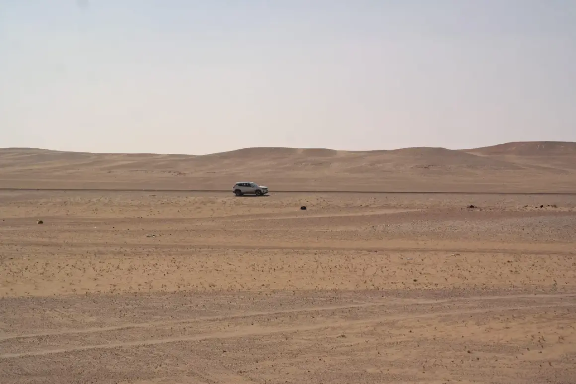 Samochód przemierza pustynny krajobraz Arabii Saudyjskiej. Czy Arabia Saudyjska jest bezpieczna? Podróż przez bezkresne piaski.