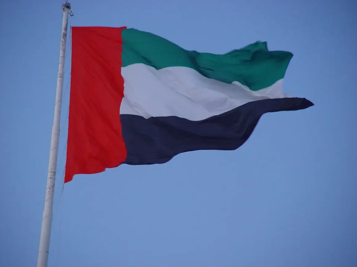 Flaga Zjednoczonych Emiratów Arabskich, znana również jako flaga Dubaju, powiewa na maszcie na tle błękitnego nieba.