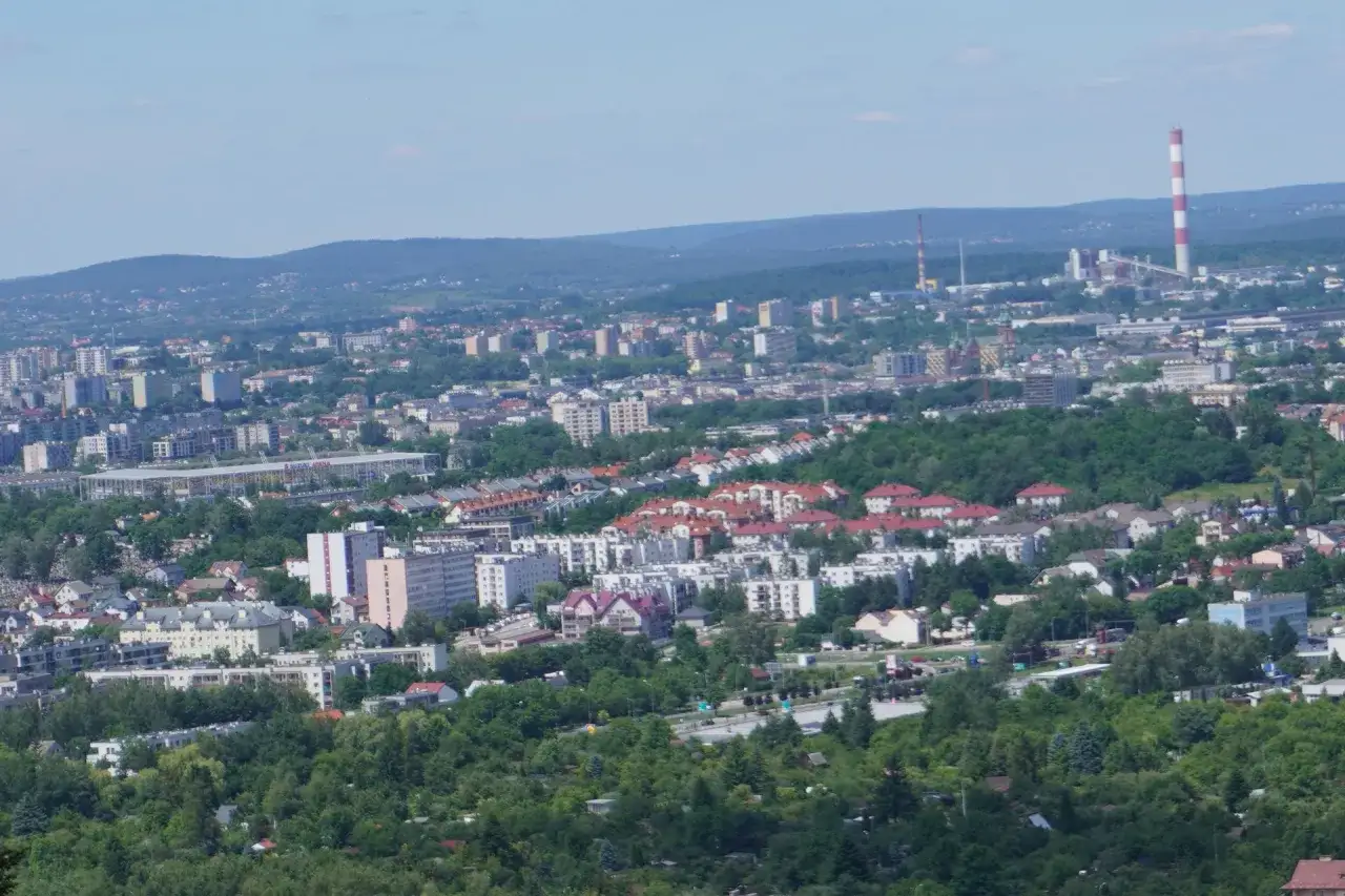 Widok na miasto Kielce, stolicę województwa świętokrzyskiego. W oddali widać kominy, a bliżej zabudowania mieszkalne i stadion.