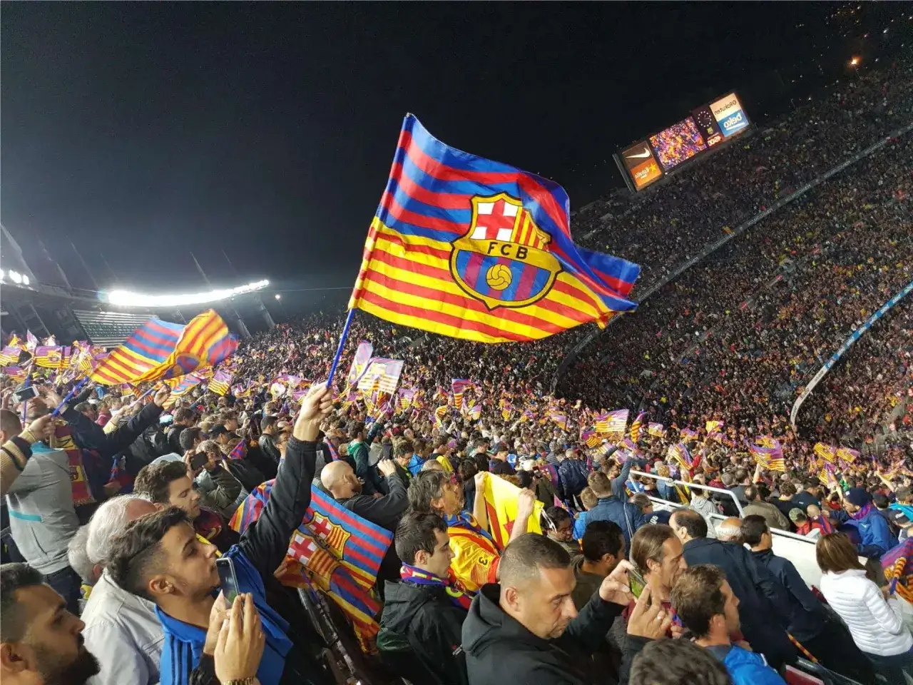 Tłum kibiców na stadionie unosi flagę Katalonii z herbem FCB.