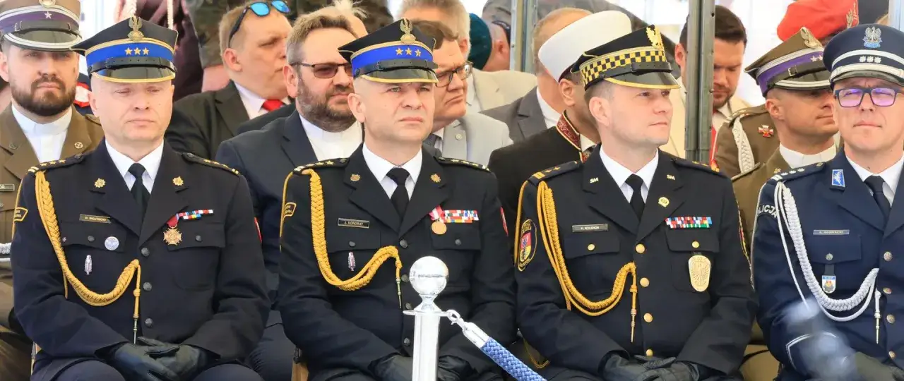 Urzędnicy w galowych mundurach, z odznaczeniami i złotymi sznurami, siedzą w pierwszym rzędzie. W tle widać innych mężczyzn w mundurach i cywilnych strojach.