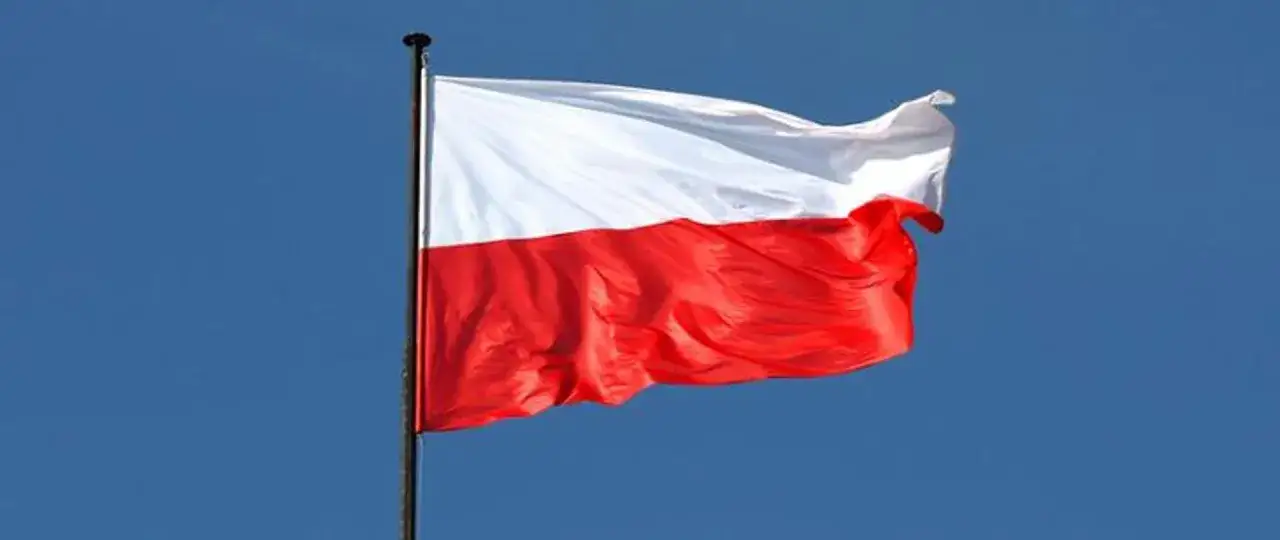Biało-czerwona flaga Polski powiewa na maszcie na tle błękitnego nieba. Czy flaga może wisieć cały rok? Tak, symbolizuje dumę i tożsamość narodową.
