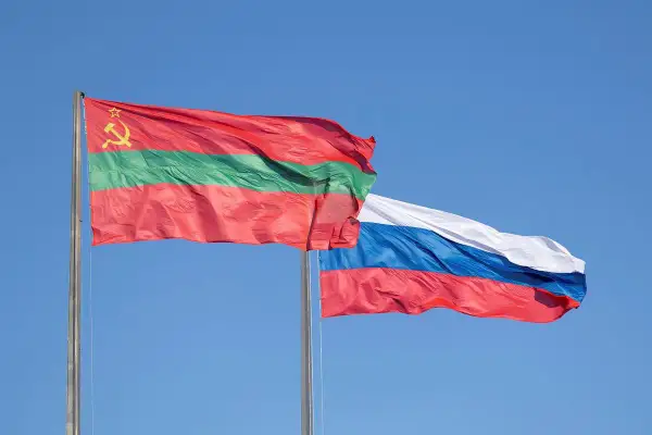 Dwie flagi powiewają na wietrze: flaga niebiesko czerwona z białym, niebieskim i czerwonym pasem oraz flaga z czerwonym, zielonym i czerwonym pasem, ozdobiona sierpem i młotem.