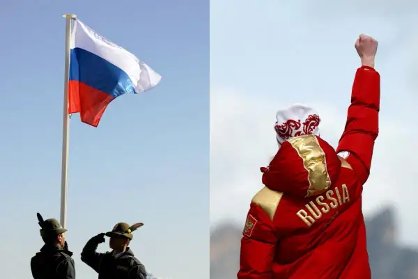 Flaga Rosji powiewa na maszcie, obok żołnierze oddają honory. Na drugim planie sportowiec w czerwonej kurtce z napisem "RUSSIA" unosi pięść w geście triumfu.