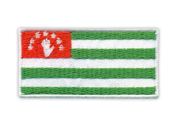 Naszywka z flagą Abchazji: czerwony prostokąt z białą dłonią i gwiazdami, obok zielono-białe pasy.