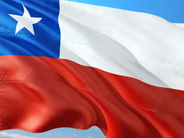 Flaga Chile powiewa na wietrze. Biały pas, czerwony pas i niebieski kwadrat z białą gwiazdą symbolizują ten kraj.