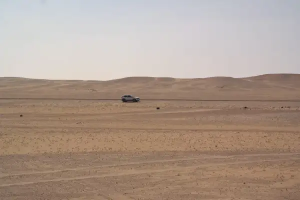 Samochód przemierza pustynny krajobraz Arabii Saudyjskiej. Czy Arabia Saudyjska jest bezpieczna? Podróż przez bezkresne piaski.