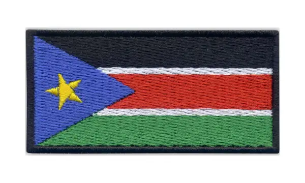 Naszywka z flagą Sudanu Południowego. Czarny pas na górze, pod nim biały, czerwony i zielony pas. Z lewej strony niebieski trójkąt z żółtą gwiazdą.
