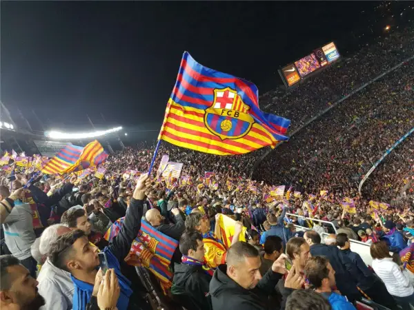 Tłum kibiców na stadionie unosi flagę FC Barcelona, symbol Katalonii.